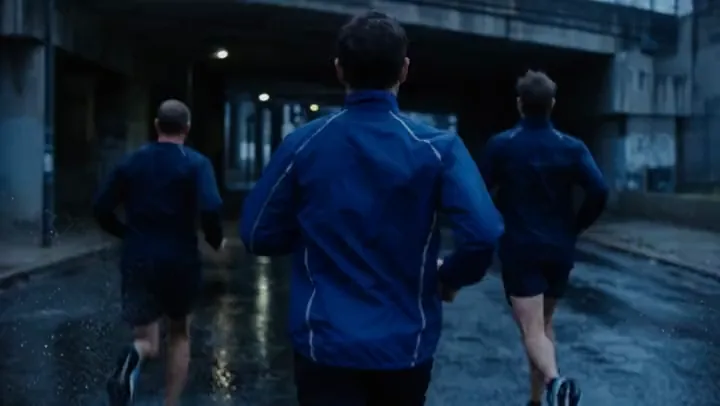 Three runners moving together beneath a city underpass
